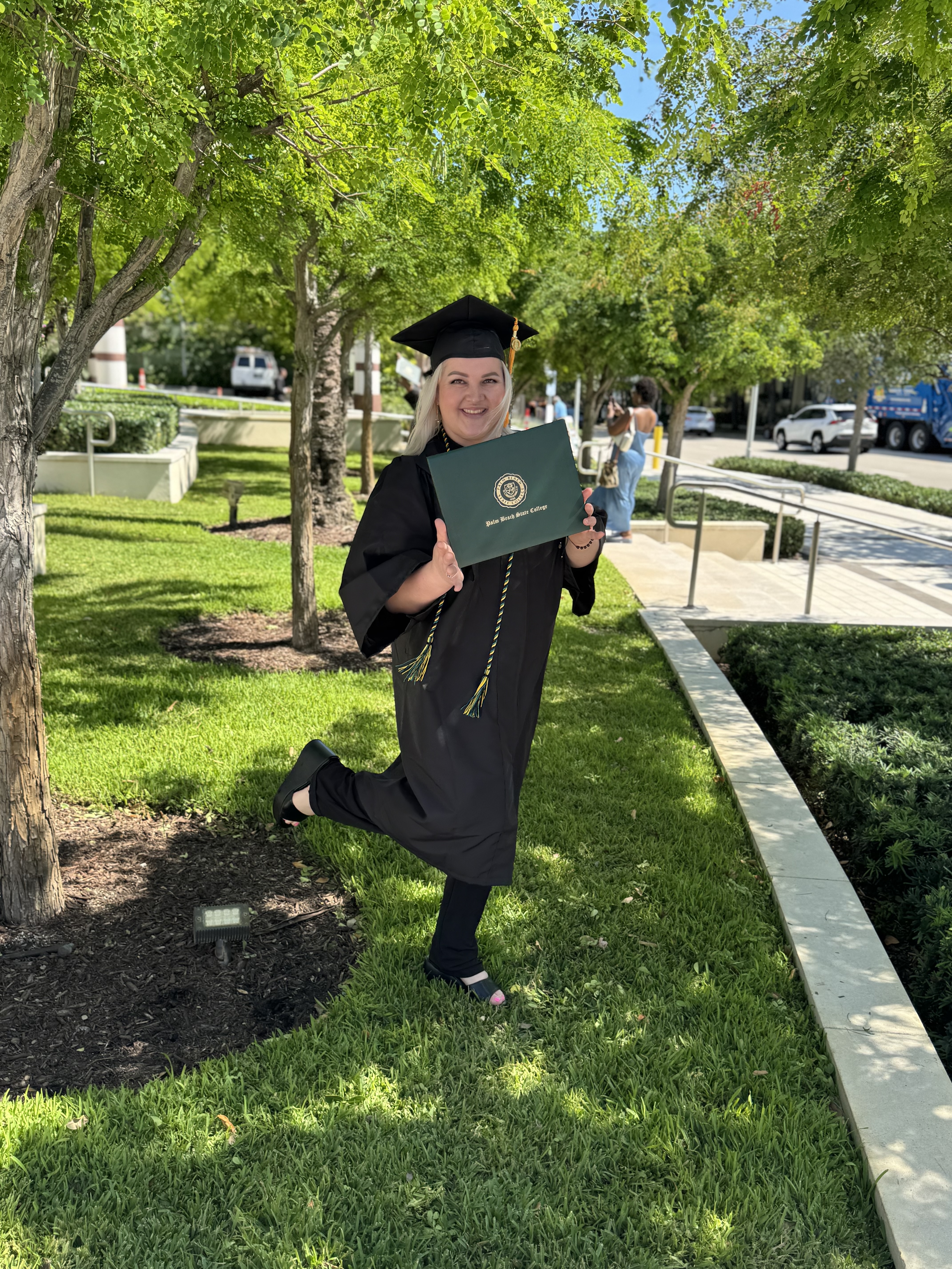 Mom in graduation gown and cap holding her degree.