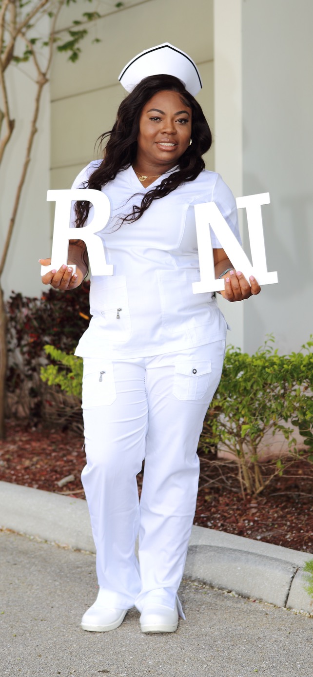 Woman in a nursing uniform holding large R N letters.